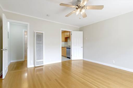 A room with a ceiling fan and wooden floors.