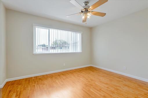 A room with a ceiling fan and a window with blinds.