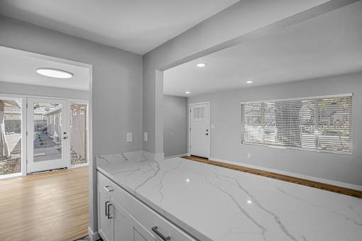 A kitchen with a marble countertop and wooden flooring.