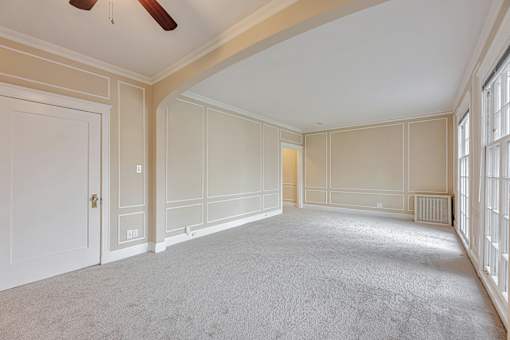 A spacious room with a carpeted floor and a ceiling fan.