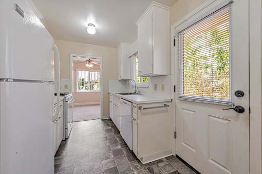 A kitchen with white appliances and cabinets.