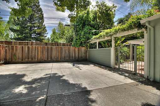 A backyard with a wooden fence and a covered patio area.