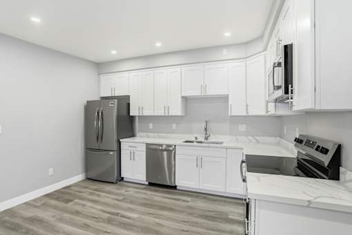 A kitchen with white cabinets and a wooden floor.