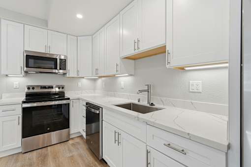 A modern kitchen with white cabinets and stainless steel appliances.