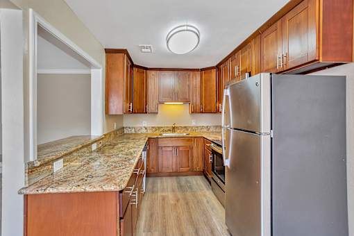 A kitchen with wooden cabinets and a granite counter top.