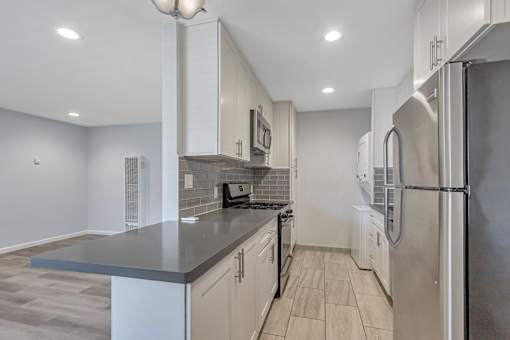 A kitchen with a refrigerator, microwave, and oven.