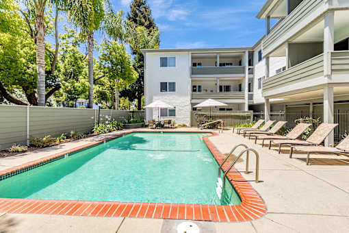 A swimming pool surrounded by lounge chairs and trees.