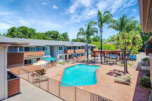 A swimming pool surrounded by a fence and chairs.