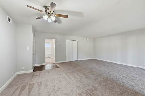 A room with a ceiling fan and carpeted floor.