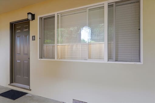 A grey door with a black mat in front of it.