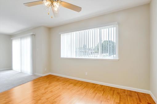 A room with a ceiling fan and a window with blinds.