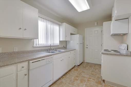 A kitchen with white cabinets and appliances.