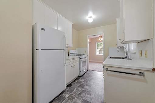 A kitchen with white appliances and a tiled floor.