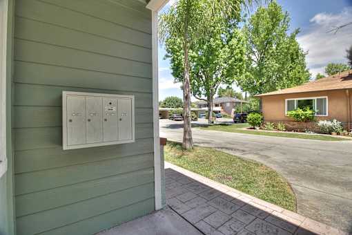 A green house with a white electrical box mounted on the side.