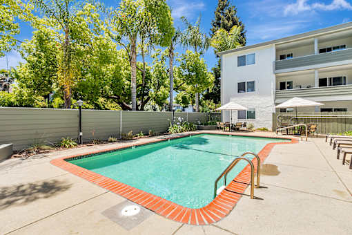 A swimming pool in a backyard with a building in the background.