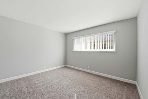 A room with a window and carpeted floor.