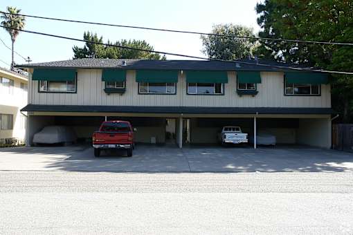 A red truck is parked in front of a two-story building.