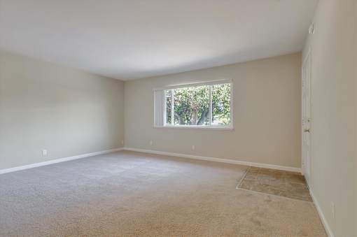 A room with a window and carpeted floor.