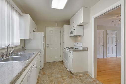 A kitchen with white cabinets and a tiled floor.