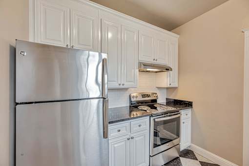 A kitchen with a stainless steel refrigerator, oven, and range hood.