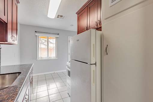 A white refrigerator in a kitchen with brown cabinets.