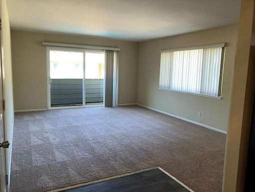 A room with a carpet floor and a window with blinds.