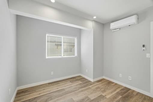 A room with wooden flooring and a window with blinds.