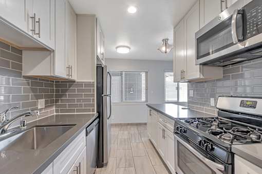 A kitchen with a stove, refrigerator, and microwave.