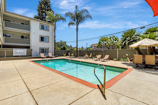A swimming pool surrounded by a concrete floor and chairs.