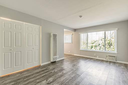 A room with a grey floor and a window with blinds.