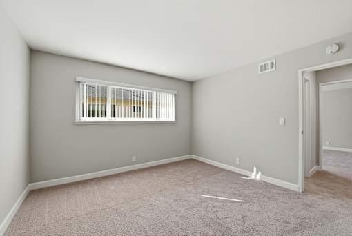 A room with a window and a door is empty and waiting to be furnished.