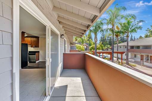 A patio with a white wall and a view of a street with cars.