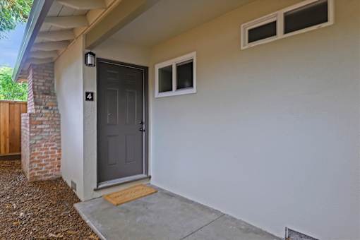 An apartment with a grey door and a small window above it.
