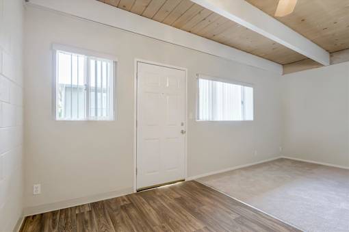 A room with a white door and a window with white blinds.