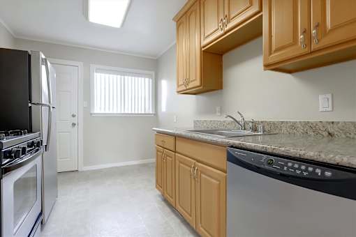 A kitchen with wooden cabinets and a marble countertop.