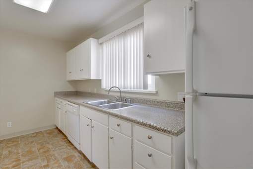 A kitchen with white cabinets and a granite countertop.