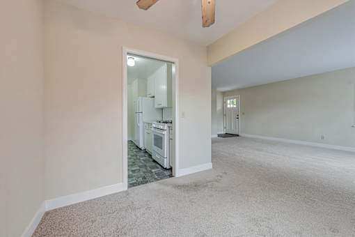 A kitchen with white appliances and a white doorway leading to another room.
