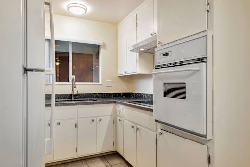 A white kitchen with a refrigerator, oven, and sink.