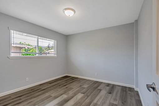 A room with a window and wooden flooring.