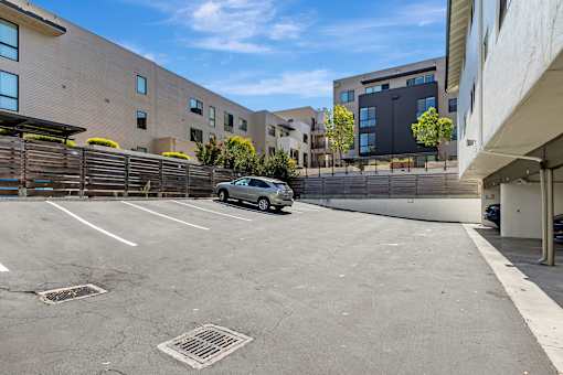 A parking lot with a car parked in the middle and buildings in the background.