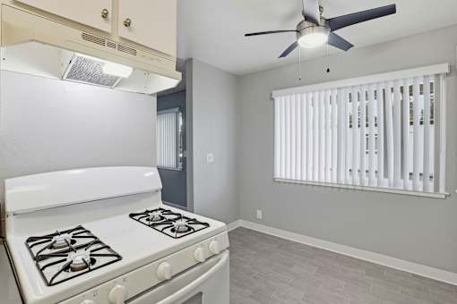 A white gas stove in a kitchen with a fan on the ceiling.