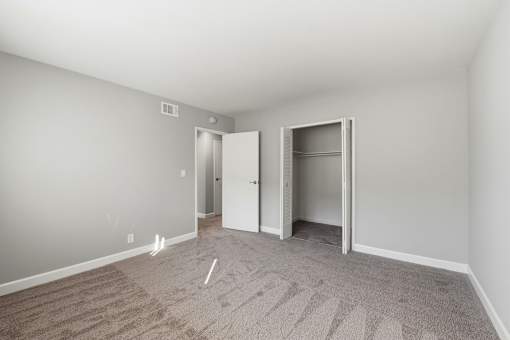 A room with a carpeted floor and two open doors.