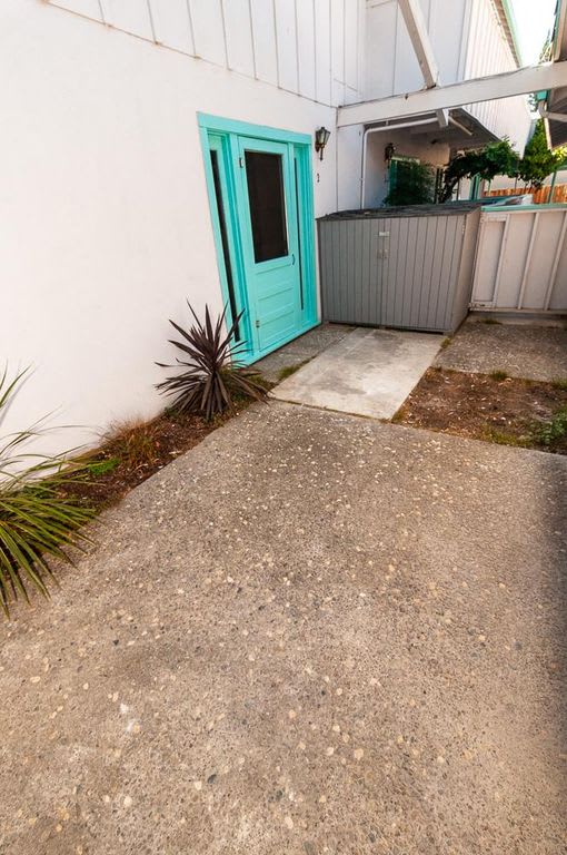 a sidewalk in front of a house with a green door