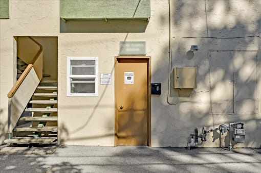 a yellow door on the side of a building with stairs