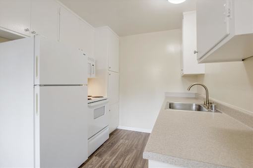 A kitchen with a white fridge and a sink.