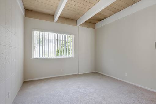 Empty room with a window and a wooden ceiling.