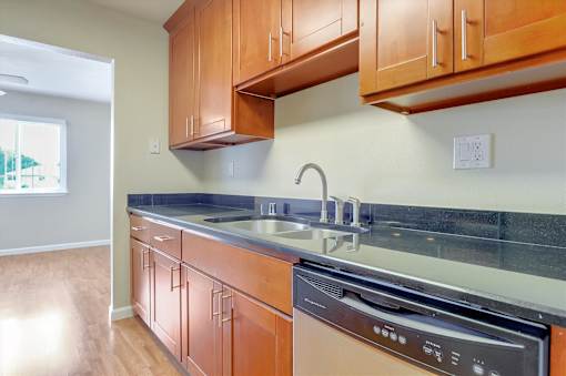 A kitchen with wooden cabinets and a black dishwasher.