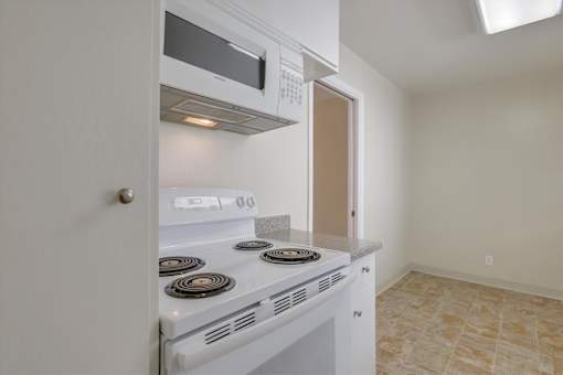 A white kitchen with a stove and microwave built into the cabinetry.