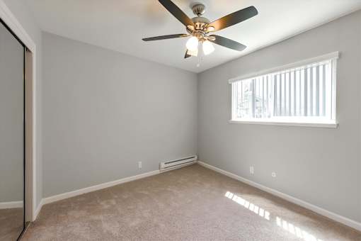 A room with a ceiling fan and a window with blinds.