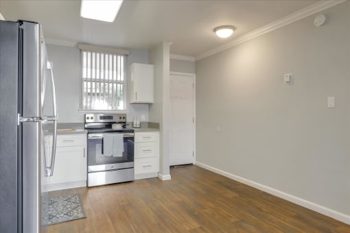 A kitchen with a refrigerator, sink, and stove.